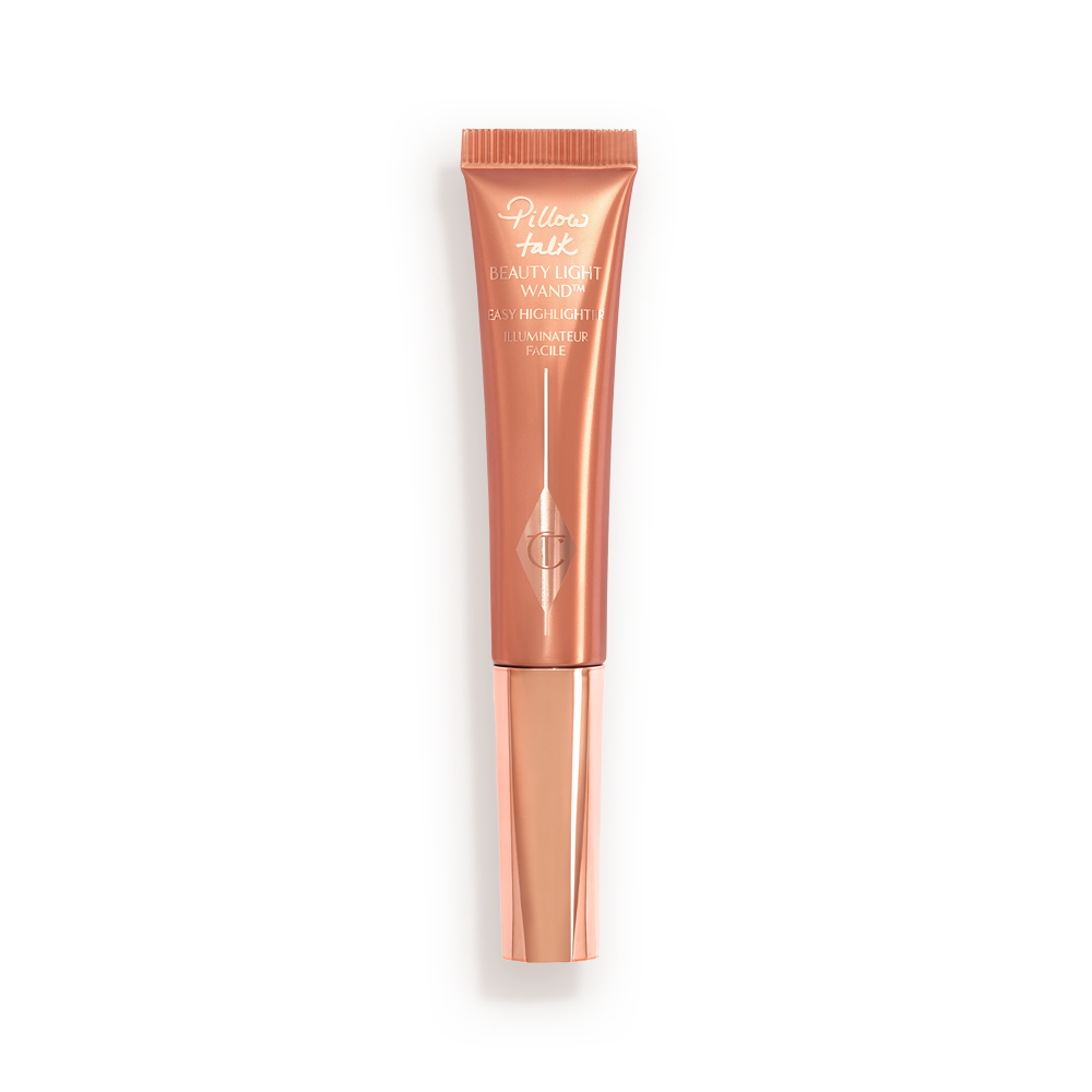 a highlighter wand, packaged in a reflective, peachy-pink tube with a rose gold cap. 