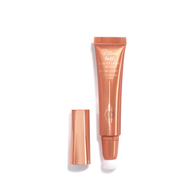 a highlighter wand, packaged in a reflective, peachy-pink tube with a rose gold cap. 