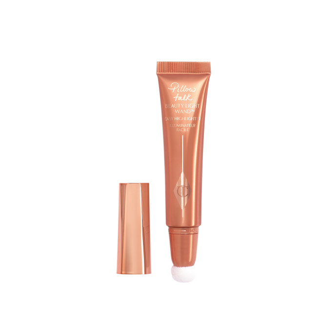 a highlighter wand, packaged in a reflective, peachy-pink tube with a rose gold cap. 