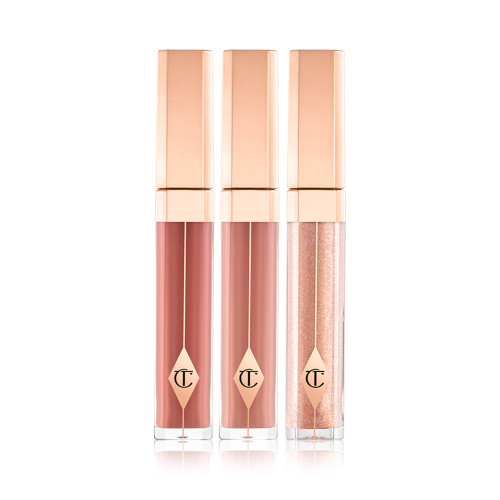 Three high-shine lip glosses in clear tubes with gold-coloured lids in medium-pink, warm brown, and sheer pink colours. 