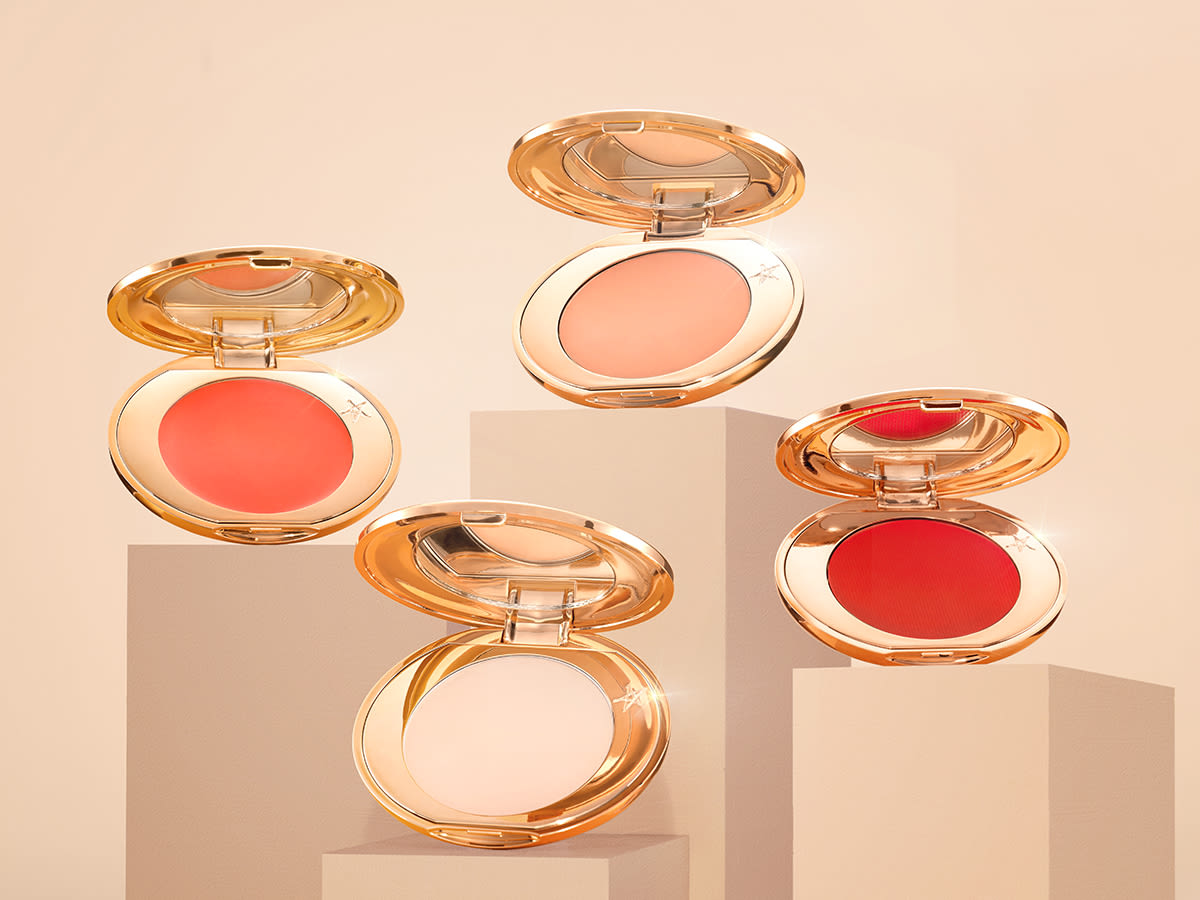 A collection of four colour corrector compacts with mirrored lids in light peach, medium-peach, orange, and burnt orange colours. 