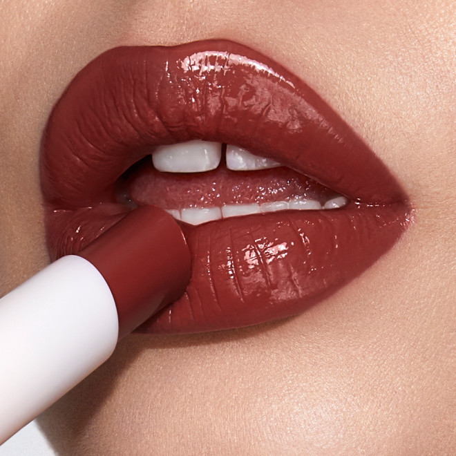 Lips close-up of a light-tone model applying a berry shade lipstick lip balm. 