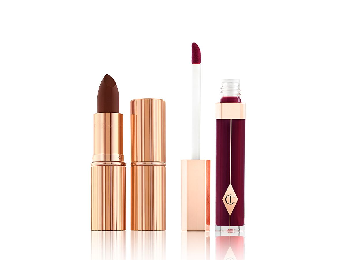 Two lipsticks, with and without lid in a dark purplish-red shade with a dark purplish-red lip gloss with its doe-foot applicator next to it. 