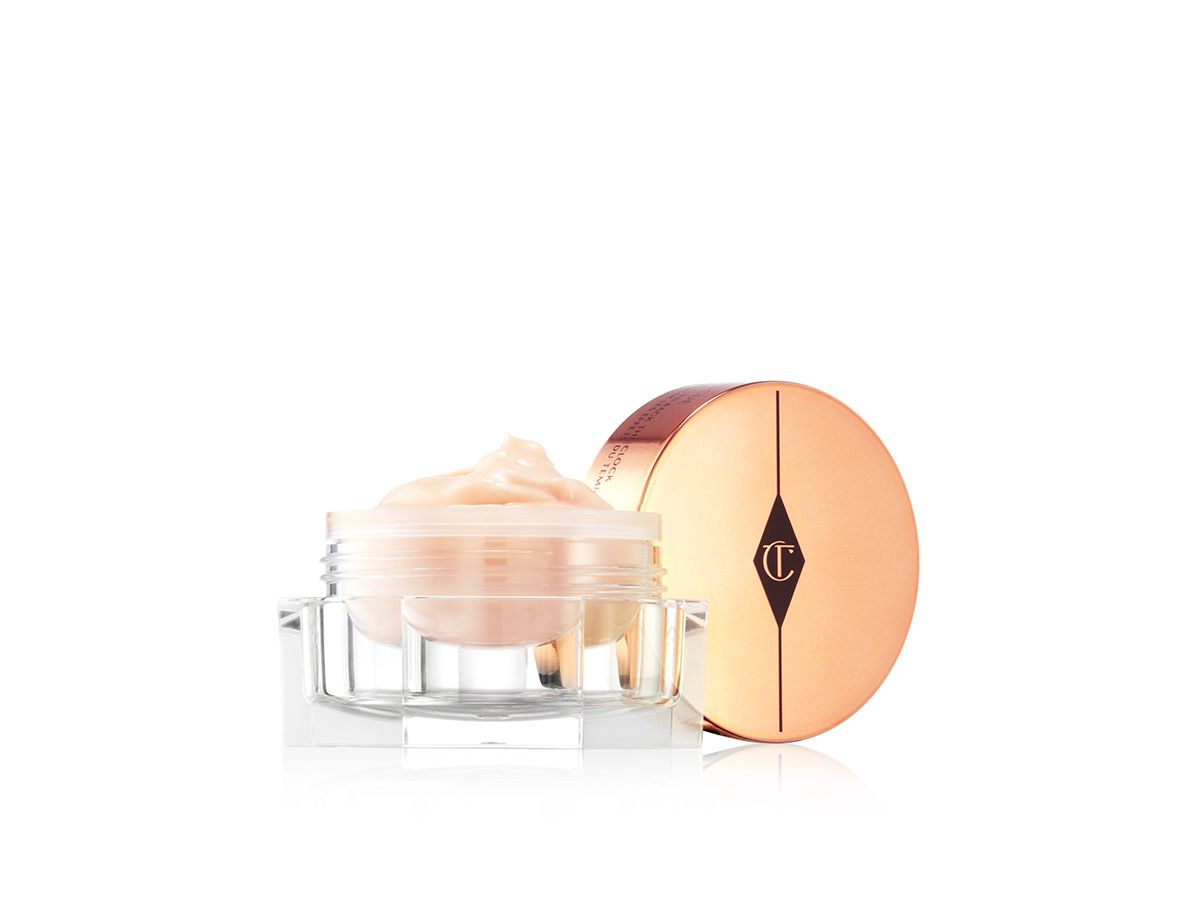 A think, champagne-coloured eye cream in a glass jar with its golden-coloured lid next to it. 