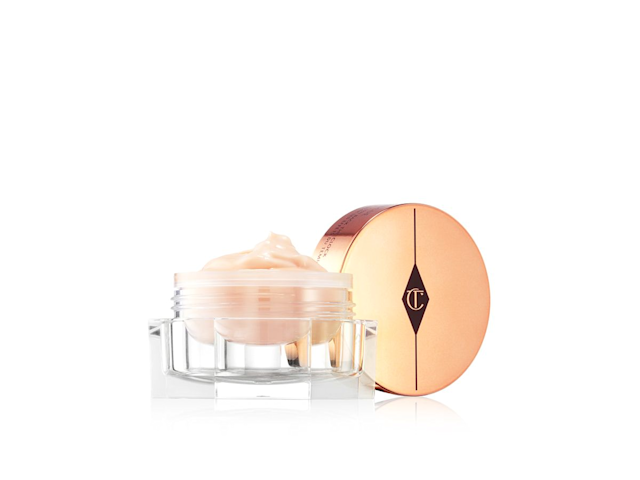 A think, champagne-coloured eye cream in a glass jar with its golden-coloured lid next to it. 