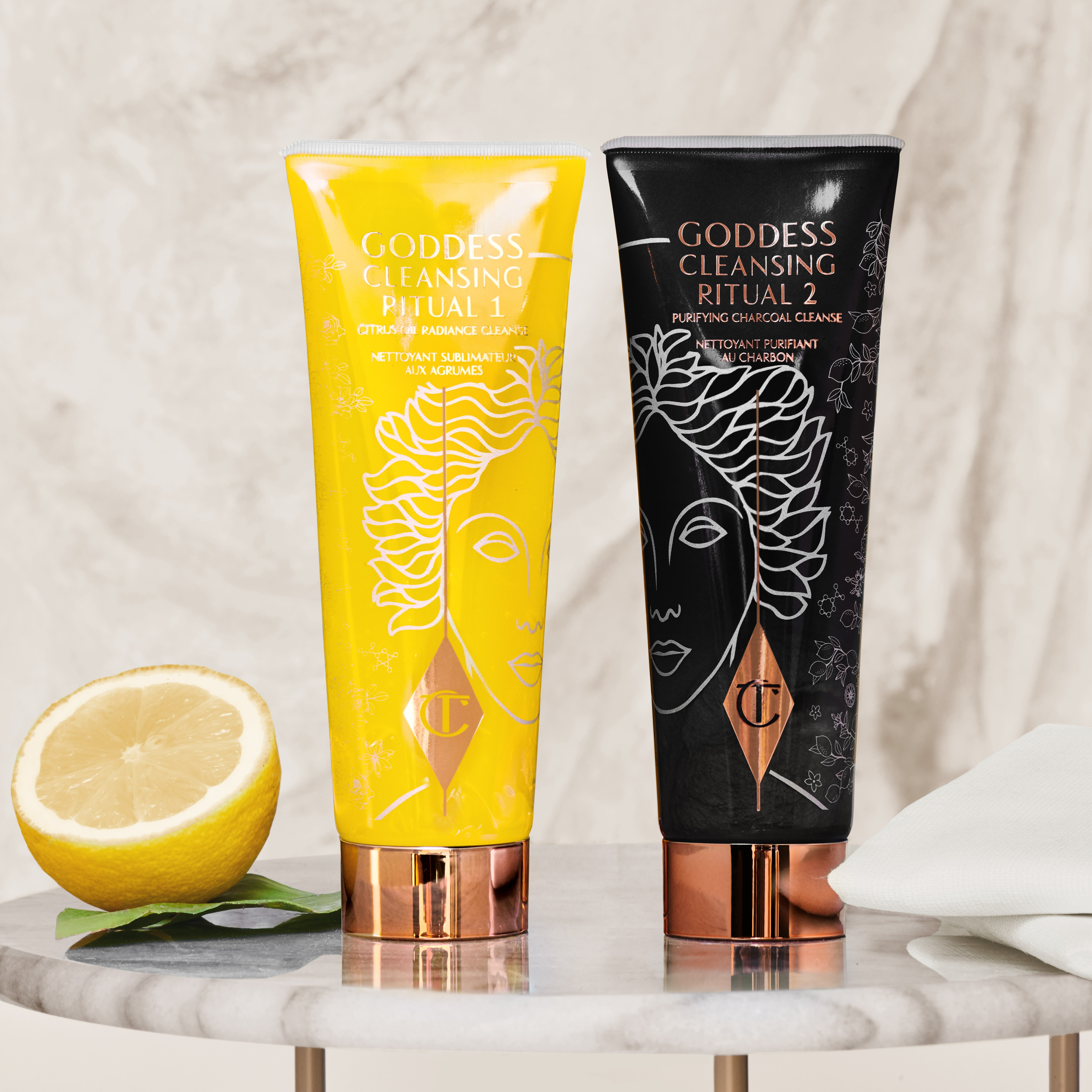 Two facial cleansers, one in lemon-yellow packaging and the other in charcoal-black, with rose-gold coloured lids. 