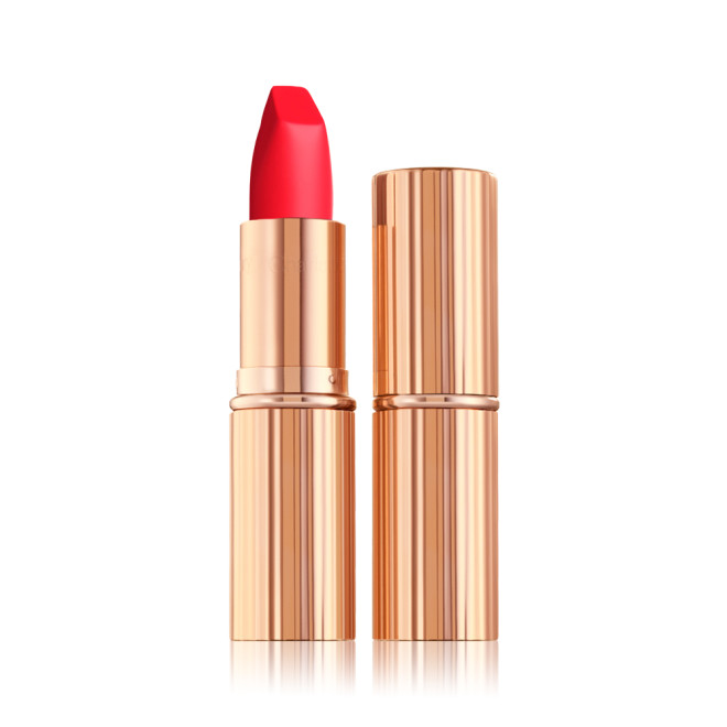 Two identical lipsticks, with and without lid, in a  classic, 70’s-inspired sunset red colour with a matte finish, in gold-coloured tubes. 