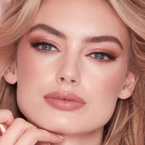 Zoomed in view of a blonde, fair skin model, wearing glowy, nude-pink makeup. 