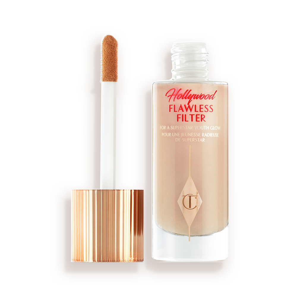 An open, luminous primer in a light cool-toned-beige shade in a glass bottle with its gold and white doe-foot applicator next to it.