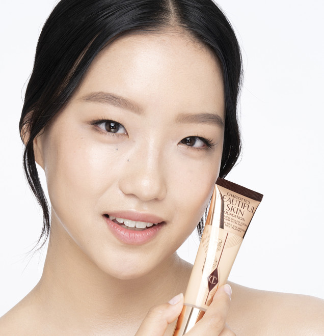 Fair-tone brunette model wearing glowy, skin-like foundation with a satin finish with nude lipstick and subtle eye makeup.