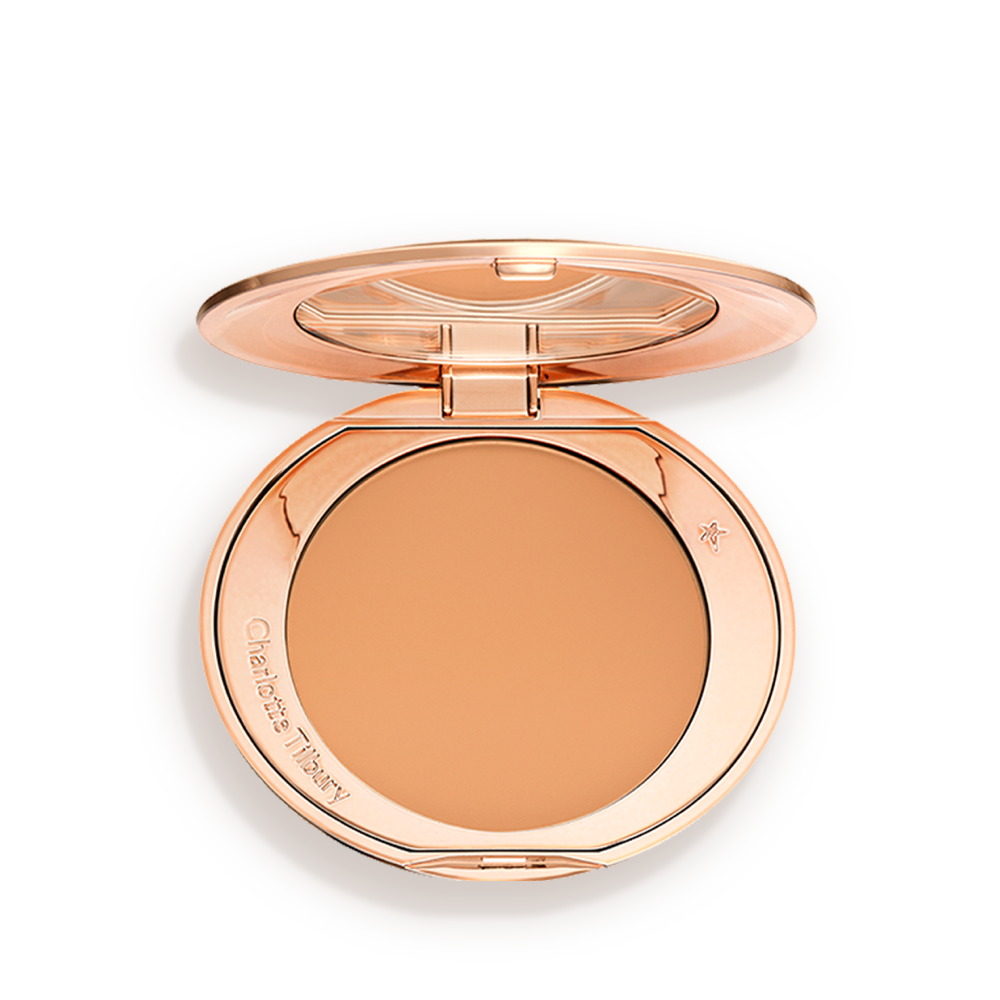 An open, pressed powder compact in a sandy-brown shade. 