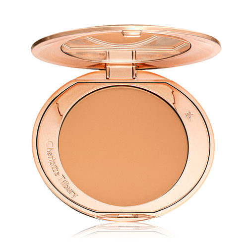 An open, pressed powder compact in a sandy-brown shade. 