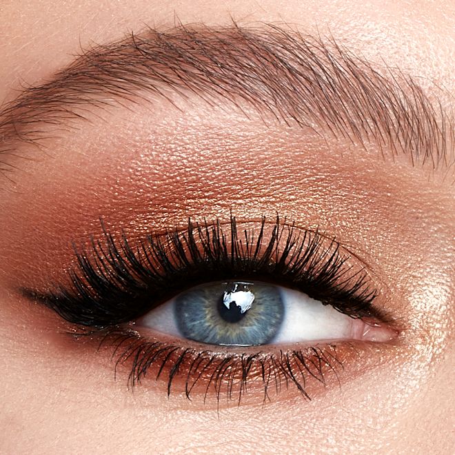 Hollywood Flawless Eye Filter in Eyes of a Star on blue-eyes close-up Single-eye close-up of a fair-tone model with blue eyes wearing metallic honey gold, soft amber, and dark chocolate brown eye makeup.