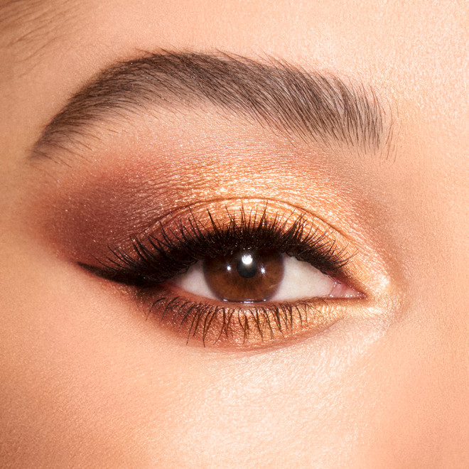 Close-up of a light-tone model's brown eyes with shimmery brown, gold, and champagne eye makeup. 