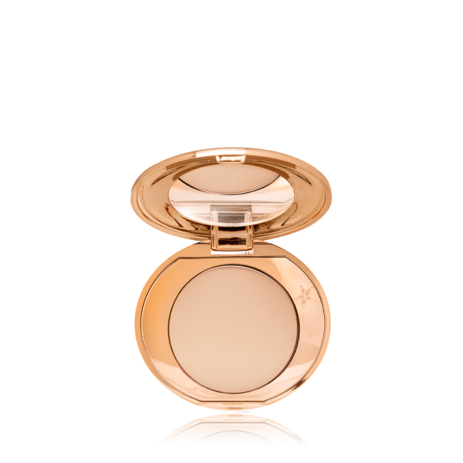 An open, mirrored-lid, mini, pressed powder compact in a light beige shade. 