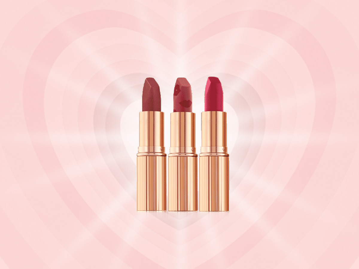 Three open, matte lipsticks in shades of dark red, dark pinkish beige, and magenta in sleek, gold-coloured tubes.