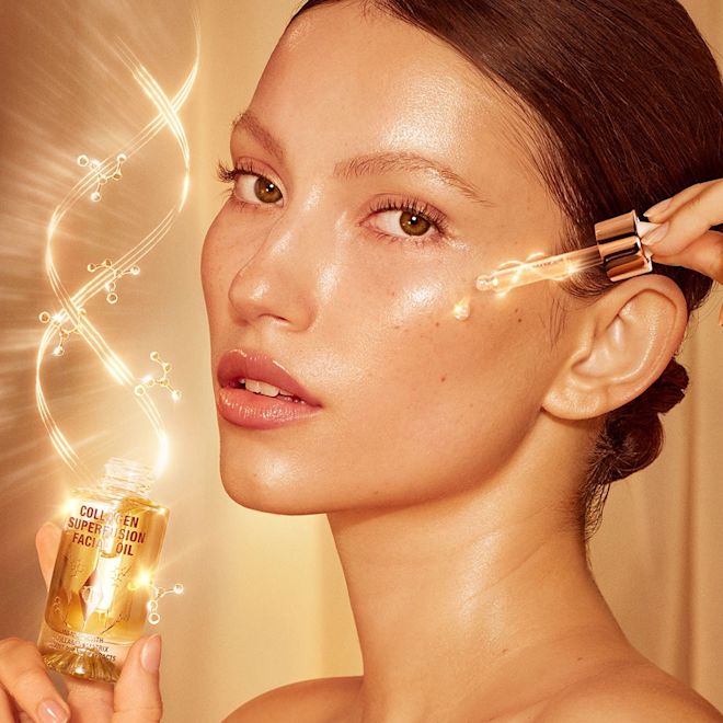 Collagen Superfusion Facial Oil on fair-tone model A fair-tone model with glowy, luminous, glass skin, applying a light-gold-coloured facial oil from a glass bottle with a gold and white-coloured dropper lid.