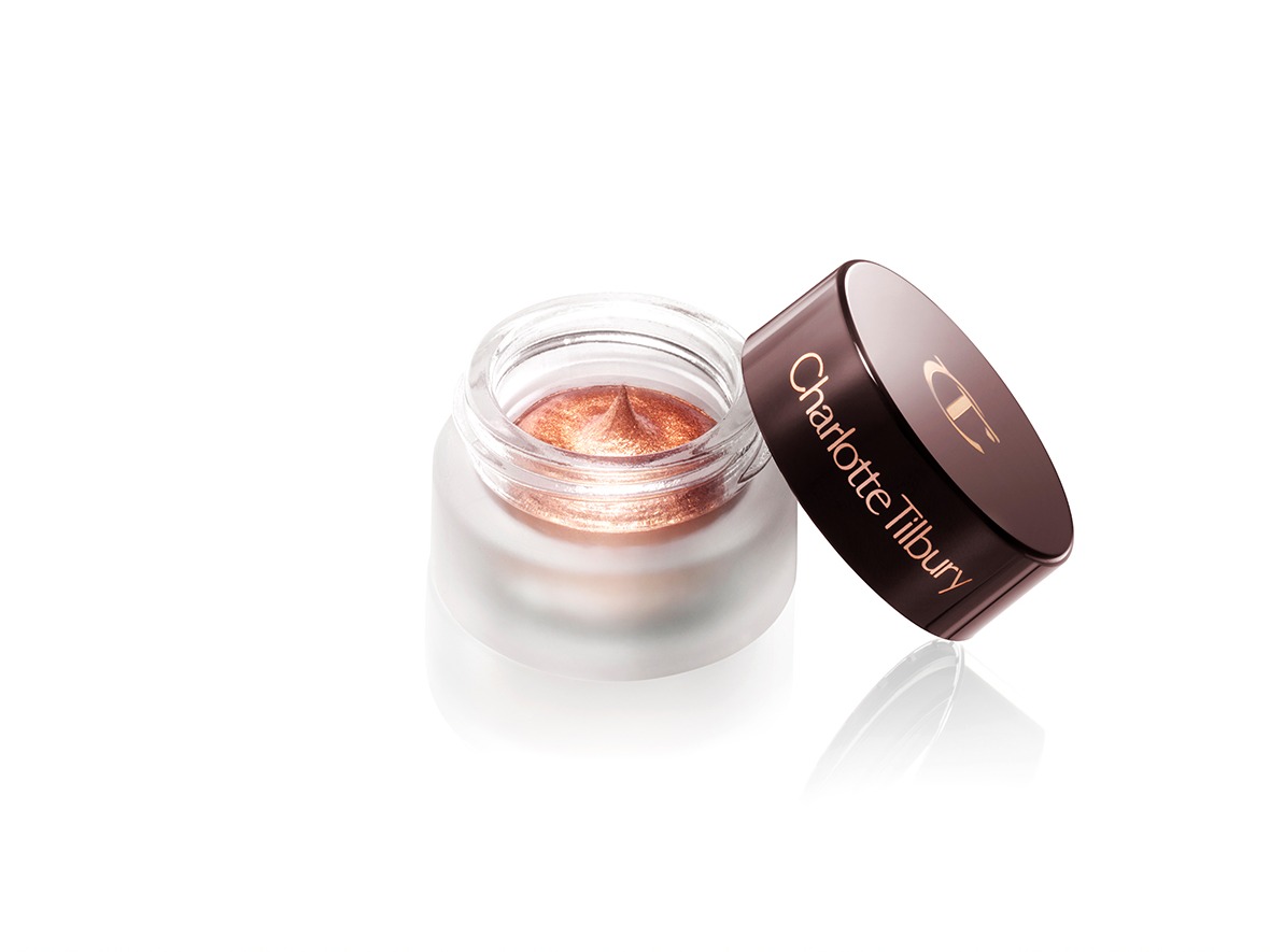 A coppery gold. cream eyeshadow in an open glass pot with a dark brown-coloured lid. 