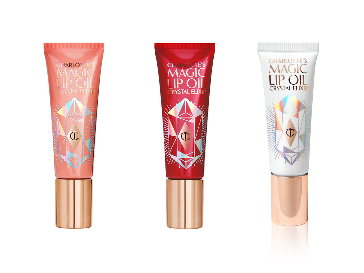 Three closed lip oils with gold-coloured lids in nude coral, poppy-red, and white-coloured tubes. 