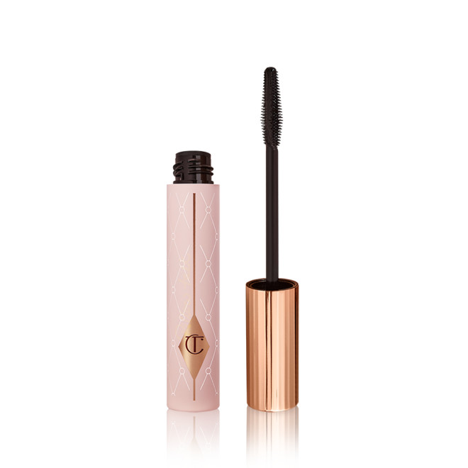 Mascara in a pink-coloured tube with its gold-coloured lid with a black applicator next to it. 