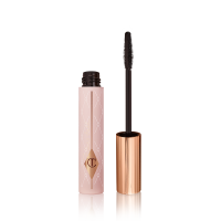 Mascara in a pink-coloured tube with its gold-coloured lid with a black applicator next to it. 