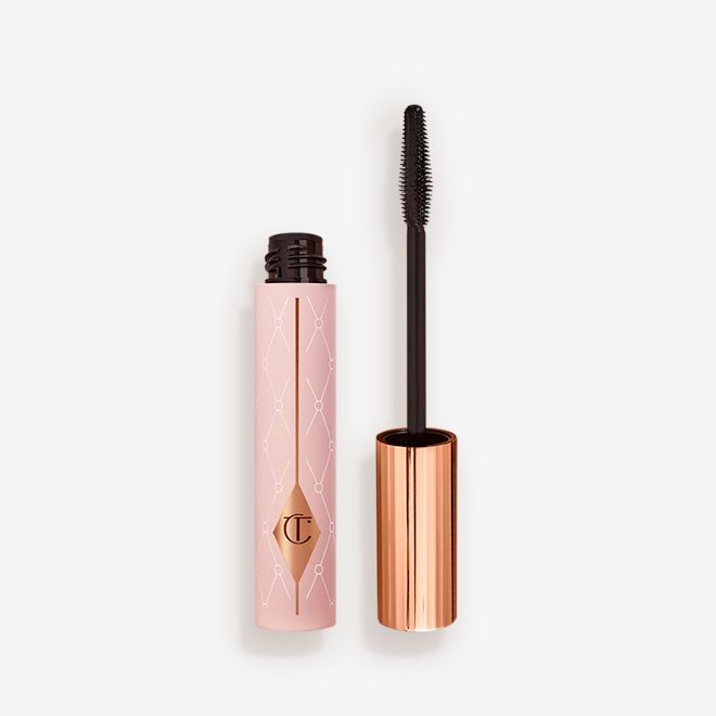 Pillow Talk Mascara open Mascara in a pink-coloured tube with its gold-coloured lid with a black applicator next to it.