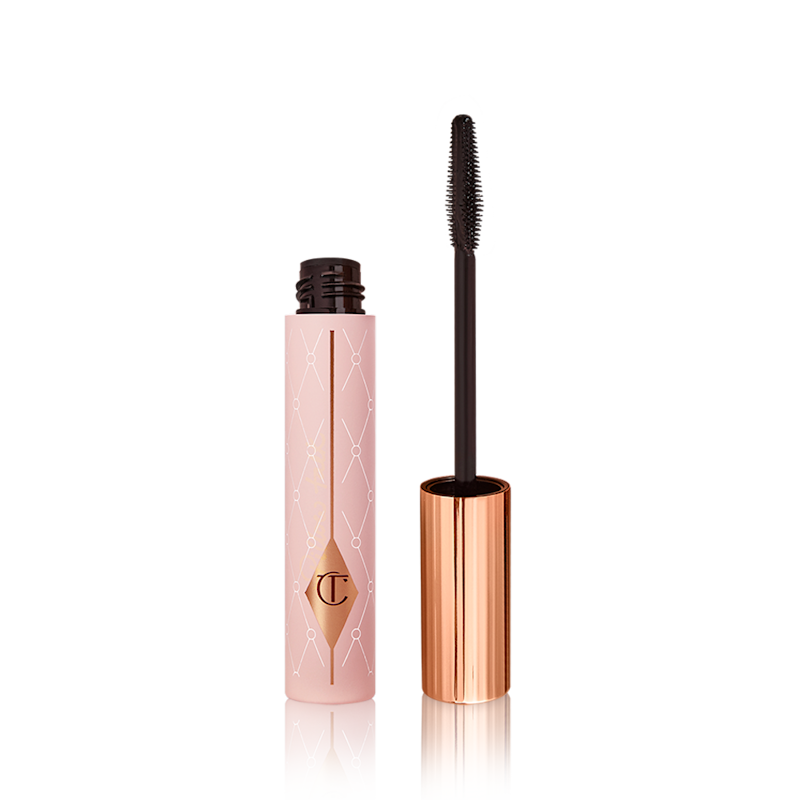 Mascara in a pink-coloured tube with its gold-coloured lid with a black applicator next to it. 