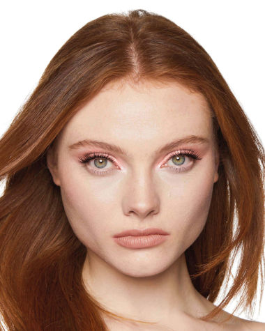 Fair-tone model with grey eyes wearing shimmery rose gold eyeshadow with nude peach lipstick. 