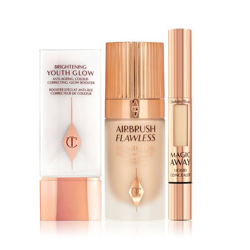A primer in white and rose gold packaging with a foundation in a frosted glass bottle and rose-gold lid, and a concealer in rose-gold packaging with a small window on the tube to see the concealer shade.