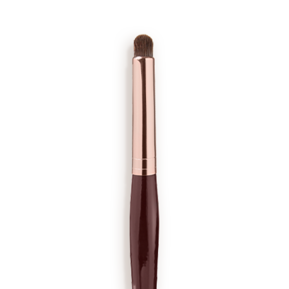 Close-up of an eyeshadow smudging brush with soft bristles and a rose-gold and dark crimson handle. 