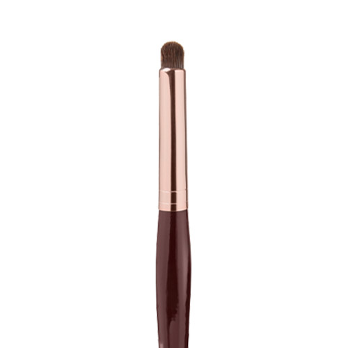 Close-up of an eyeshadow smudging brush with soft bristles and a rose-gold and dark crimson handle. 