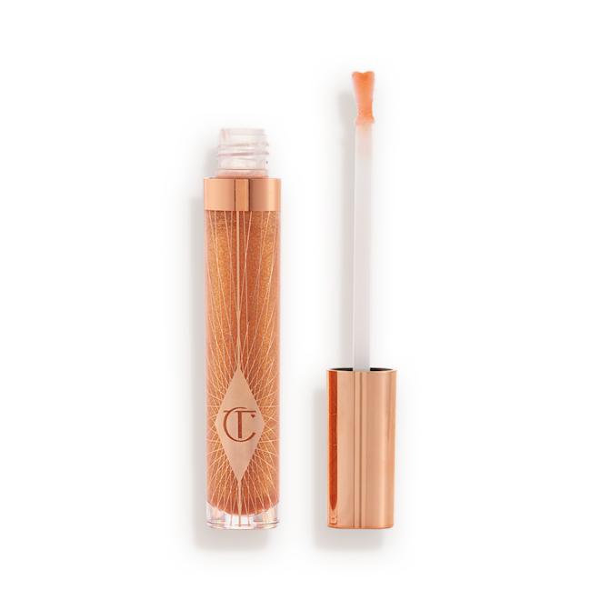 Collagen Lip Bath in Gold lid removed A lip gloss in a sheer gold shade in a glass tube with its heart-shaped applicator next to it.