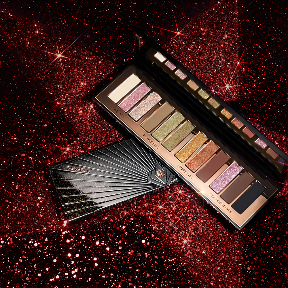 Red and black-coloured galaxy-theme banner with an open and closed, 12-pan eyeshadow palette with matte and shimmery shades in beige, pink, gold, green, brown, peach, and black.