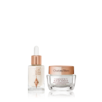 A travel-size pearly-white serum in a glass bottle with a travel-size face cream in a glass jar, both having a rose-gold and white colour scheme. 