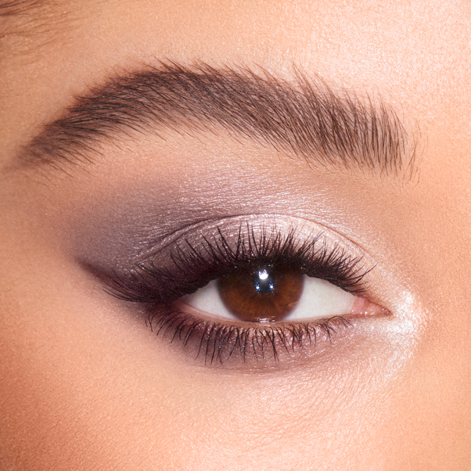 Close-up of a light-tone model's brown eye with shimmery grey, pearl, and silver eye makeup. 