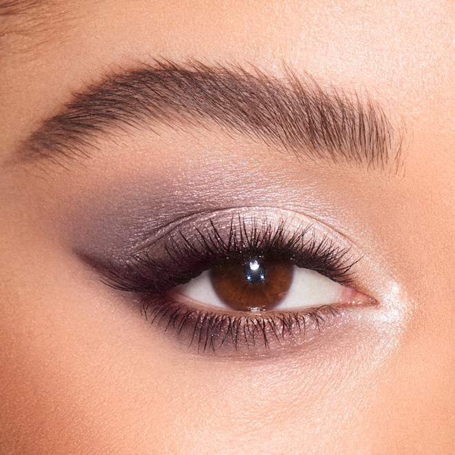 Close-up of a light-tone model's brown eye with shimmery grey, pearl, and silver eye makeup. 