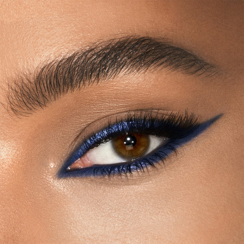 Medium-tone model eye close-up of shimmery cobalt blue eyeliner on the upper lid and lower water line. 