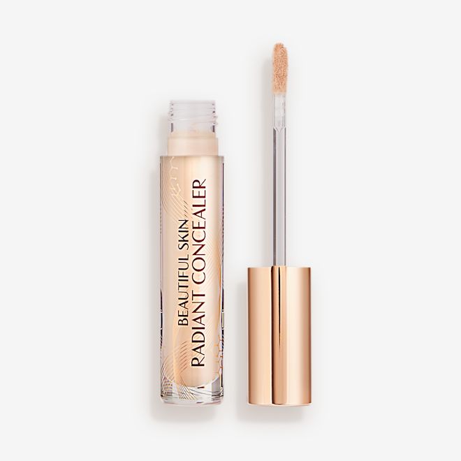 Beautiful Skin Radiant in Concealer in 3.5 lid removed Radiant concealer in a glass tube with its doe-foot applicator next to it with a gold-coloured handle.