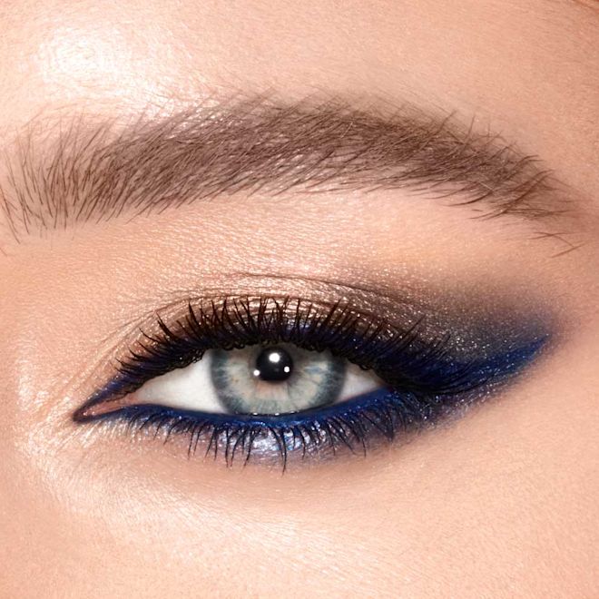 Luxury Palette in Super Blue on blue eyes close-up Eye close-up of a model with grey-blue eyes wearing shimmery gold and navy blue eye makeup that makes her eye colour pop.