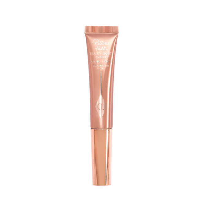 A liquid highlighter wand in a pearlescent rose-gold plastic tube with its nude-pink box next to it. 