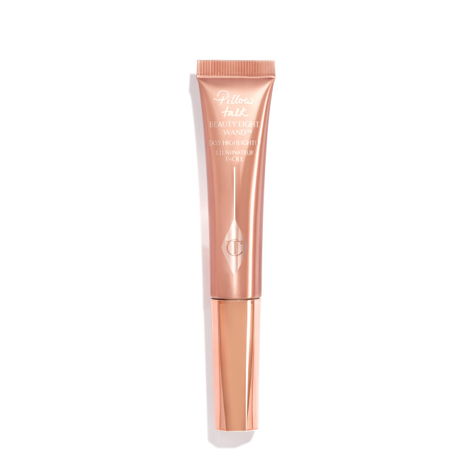 A liquid highlighter wand in a pearlescent rose-gold plastic tube with its nude-pink box next to it. 