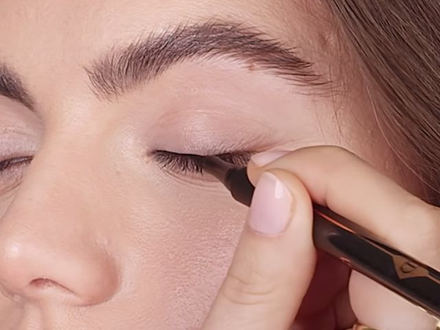 Close-up of a light-tone model getting black eyeliner applied. 