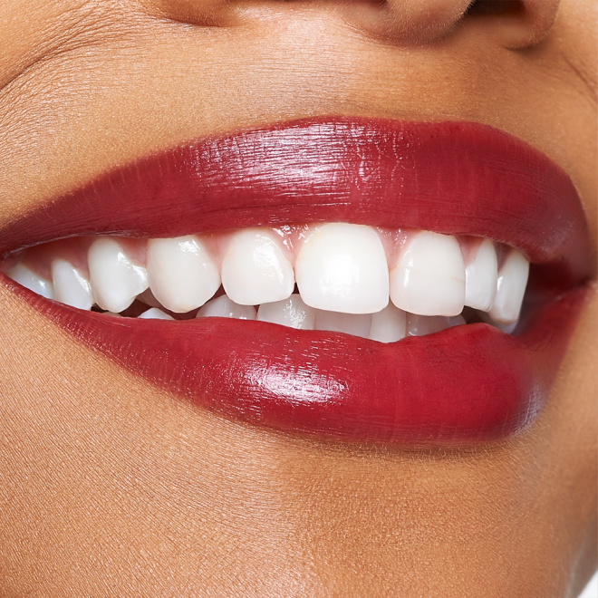 Lips close-up of a medium-tone model wearing a vibrant, cherry-red lip tint.