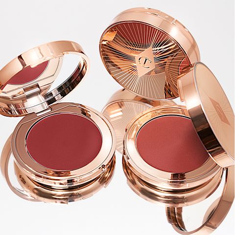 A collection of lip and cheek cream tints in berry-pink and peachy-pink shades in gold-coloured compacts.