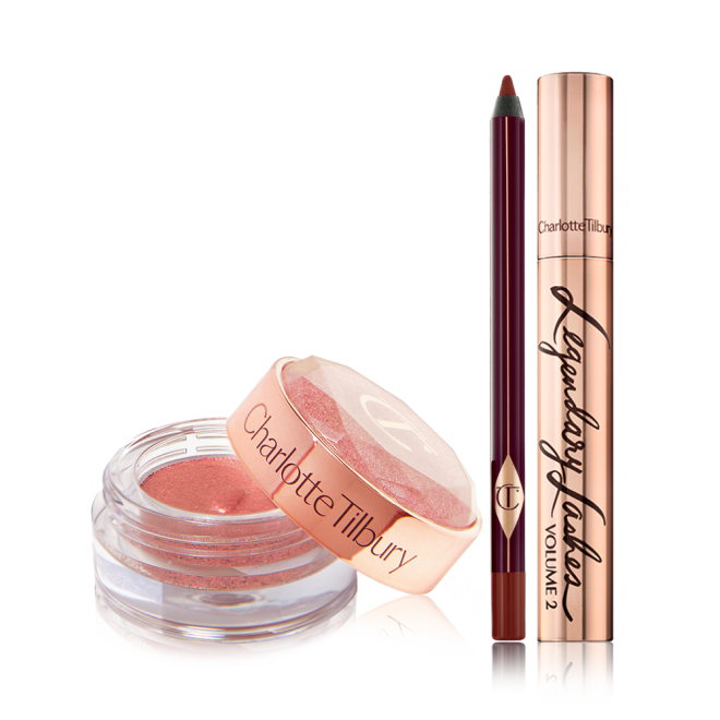 A cream eyeshadow in a berry-pink shade in a glass pot with a berry-pink eyeliner pencil, and a black mascara in gold packaging.