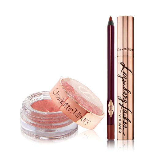 A cream eyeshadow in a berry-pink shade in a glass pot with a berry-pink eyeliner pencil, and a black mascara in gold packaging.