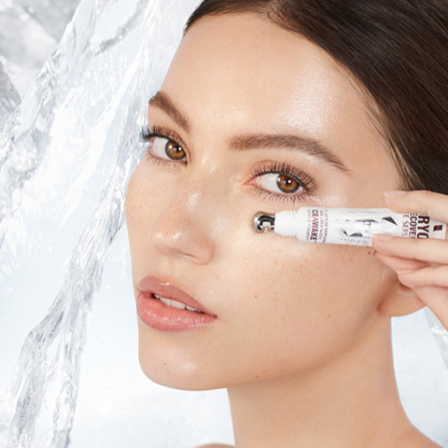 Fair-tone model with flawless, poreless, and glowy skin applying a white-coloured eye serum under her eyes that delivers a cooling sensation and moisturises. 