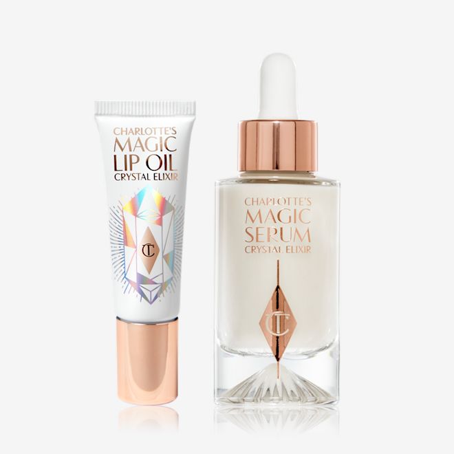 Magic Lip Oil and Magic Serum Bundle A lip oil in white and rose-gold packaging and a pearly-white face serum in a frosted glass bottle with a dropper, in a rose-gold and white colour scheme.