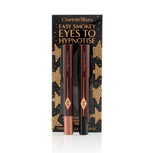 Two chubby eyeshadow sticks, in coppery-brown and black, with their packaging box behind them with text, 'Easy smokey eyes to hypnotise' written on it.