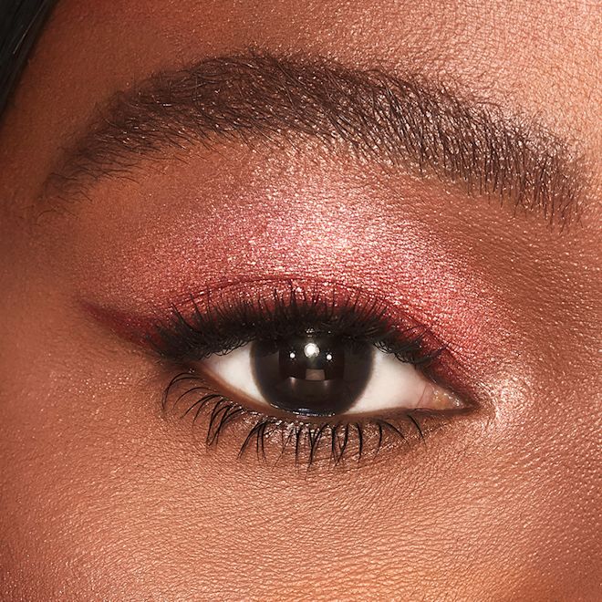 Jewel Pot in Walk of No Shame on deep tone model close-up Single-eye close-up of a deep-tone model with brown eyes wearing shimmery berry-pink eyeshadow.